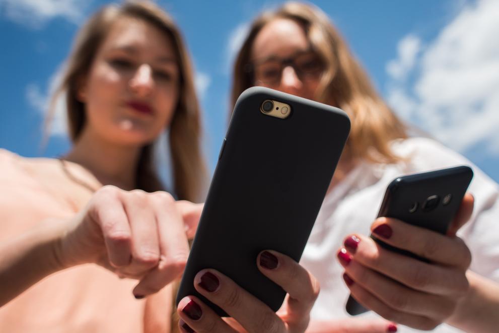 two girls looking at their mobile phones