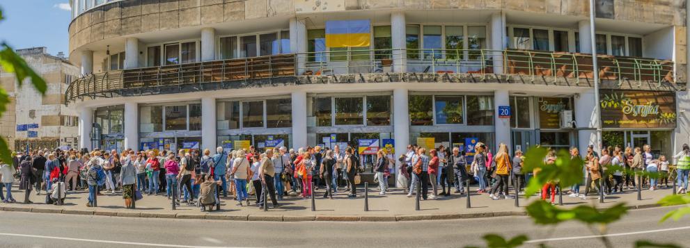 Picture of a shop with a Ukrainian flag and many people mingling outside