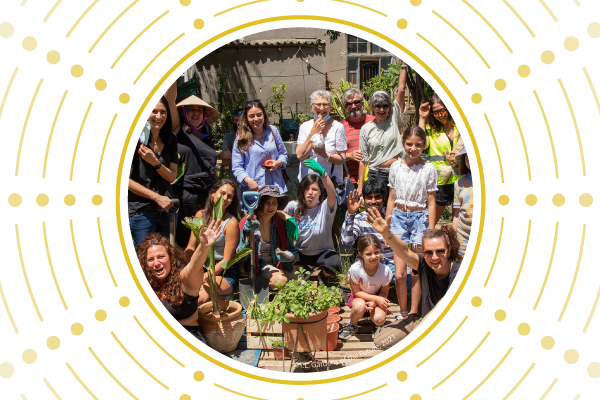 A group of people of various ages look at camera from the community garden, ‘Gardens of the Future’
